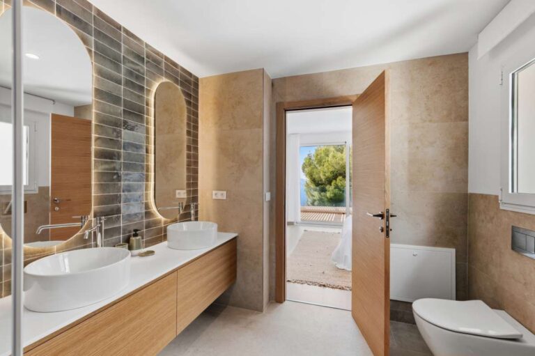 En-suite bathroom inside a modern villa in Altea Hills with double vanity, arched mirrors, toilet and access towards the terrace