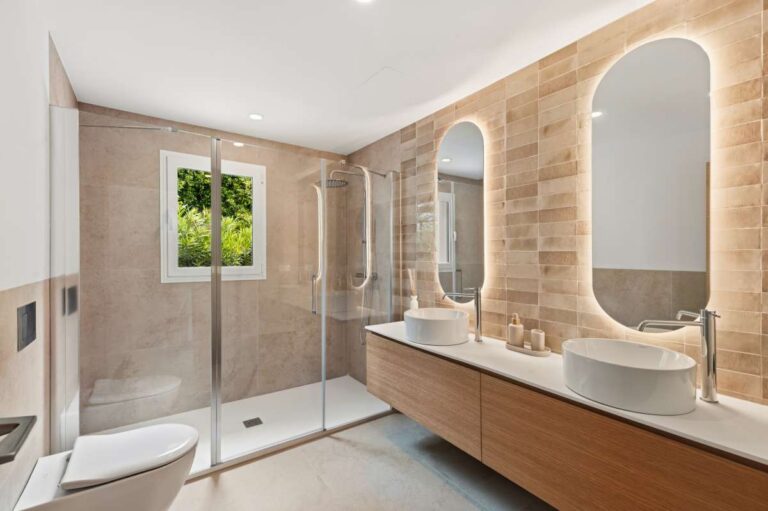 En-suite bathroom inside a modern villa in Altea Hills with double vanity, walk-in shower, arched mirrors and warm tiled finish