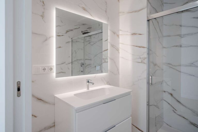 En-suite bathroom inside a modern villa in La Calalga, Calpe with illuminated mirror, vanity unit and marble-effect tiled finish