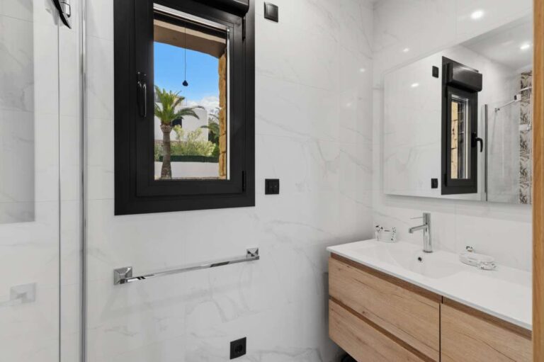En-suite bathroom inside a premium coastal villa on the Benissa Costa with double vanity, large mirror, window and bright tiled finish
