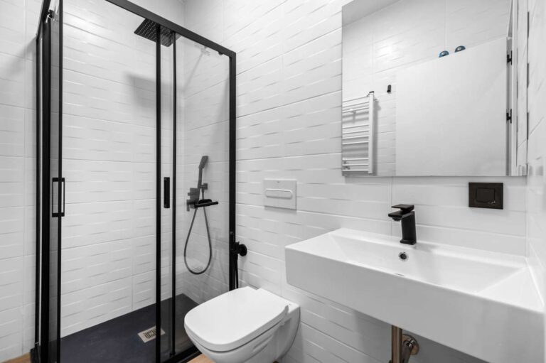 En-suite bathroom inside a single-level modern villa in Santa Clara, Altea with walk-in shower, vanity unit, toilet, black fittings and modern white tiled finish