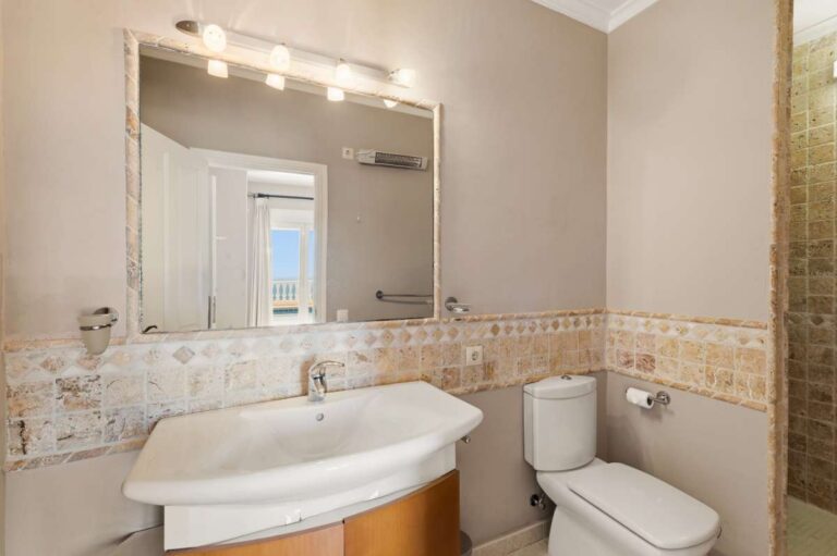 En-suite bathroom inside an Altea Hills villa with vanity unit, toilet, large mirror and bright tiled finish