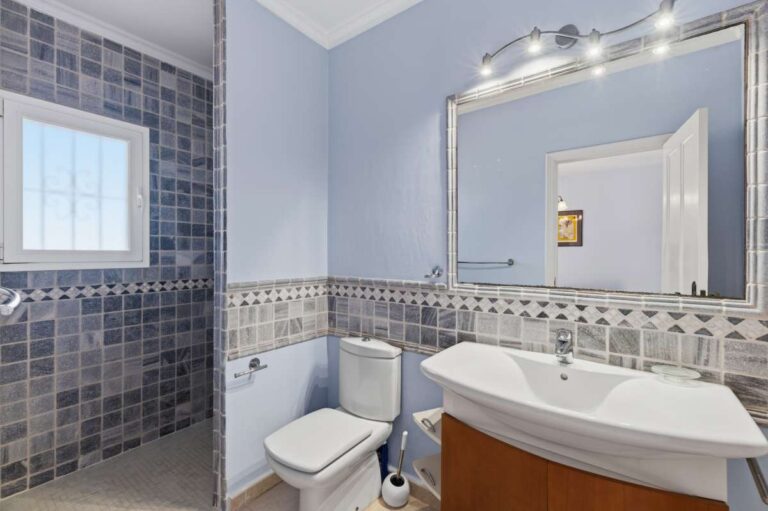 En-suite bathroom inside an elegant Mediterranean villa in Altea Hills with bath, vanity unit, toilet and blue tiled finish