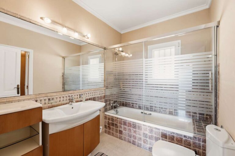 En-suite bathroom inside an elegant Mediterranean villa in Altea Hills with bathtub, double vanity, glass screen and bright tiled finish
