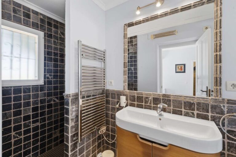 En-suite bathroom inside an elegant Mediterranean villa in Altea Hills with vanity unit, large mirror, towel radiator and tiled finish
