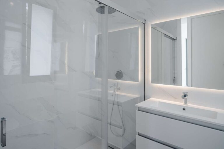 En-suite shower room inside a modern second-line sea villa in La Calalga, Calpe with illuminated mirror, vanity unit and glass shower screen