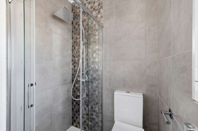 En-suite shower room inside a renovated single-level villa in Moraira with walk-in shower, toilet, window and modern tiled finish