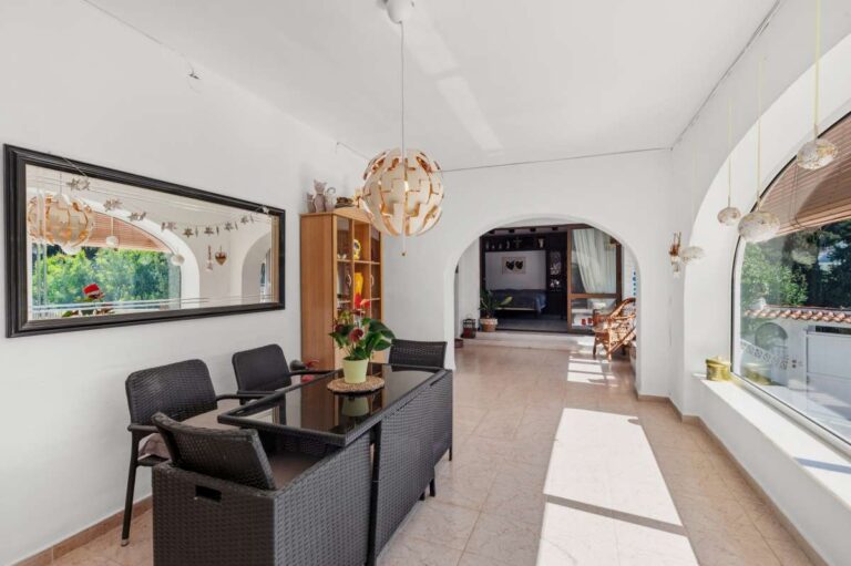 Enclosed dining area inside a Mediterranean villa in Benissa Costa near Cala Baladrar with terrace windows, seating and garden views