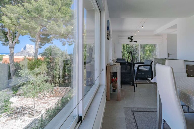 Enclosed terrace inside a modern villa in Calpe with large windows, seating area and garden views