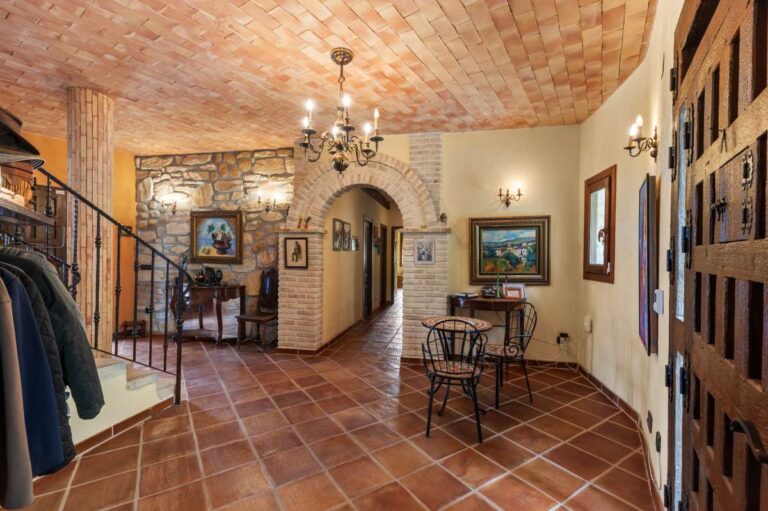 Entrance hall inside a finca-style villa in Benissa Costa with terracotta tiled floor, arched doorway, stone details and rustic Mediterranean character