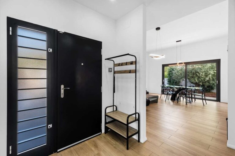 Entrance hall inside a single-level modern villa in Santa Clara, Altea with black security door, wood flooring and bright contemporary interior