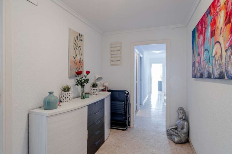 Entrance hallway inside a beachfront apartment by La Fossa Beach in Calpe with storage furniture, decorative artwork and bright modern finish