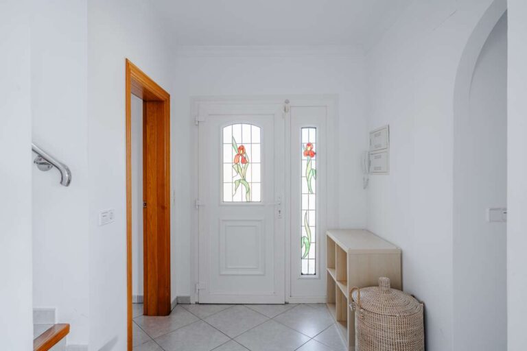 Entrance hallway inside a villa in Calpe with white walls, tiled floor and front door with natural light