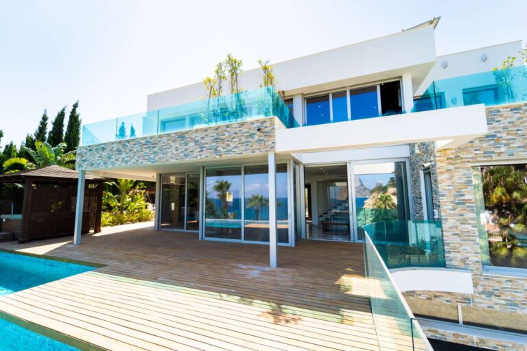Exterior of a luxury villa in Calpe with infinity pool, glass terraces, stone detailing and large sliding doors to the living area
