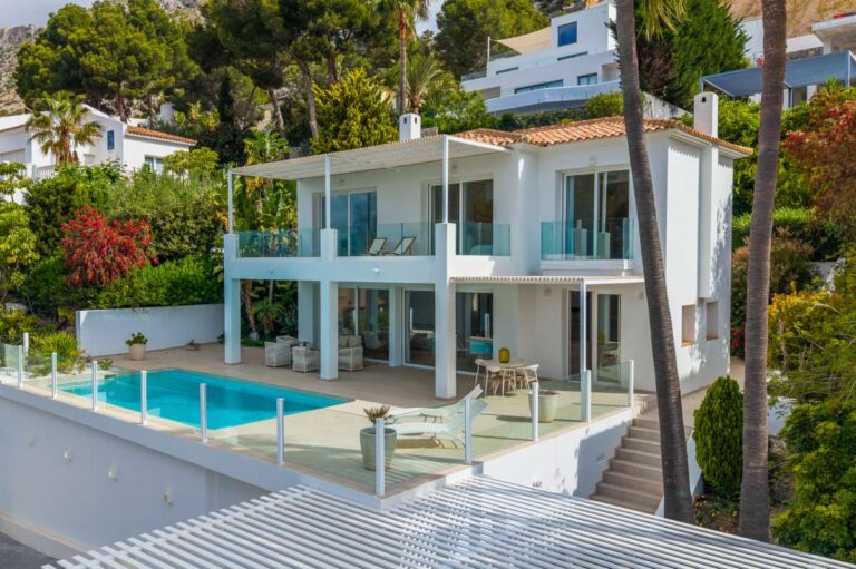 Exterior of a modern villa in Altea Hills with private swimming pool, glass terraces, white façade and Mediterranean garden surroundings