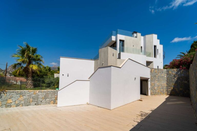 Außenansicht einer neu erbauten Luxusvilla in der Nähe des Yachthafens Puerto Blanco in Calpe mit moderner Architektur, Steinmauern, unterer Terrasse und Bergblick