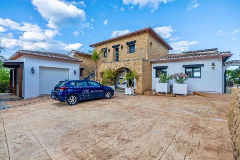 Exterior of a premium coastal villa on the Benissa Costa with private driveway, garage, stone façade, Mediterranean planting and parking area