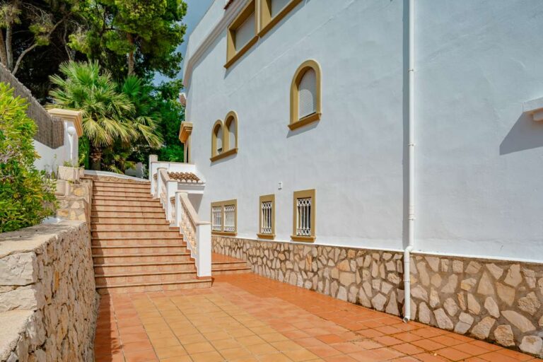 Exterior staircase at a duplex apartment near Les Platgetes Beach in Moraira with white façade, tiled walkway and Mediterranean-style building details