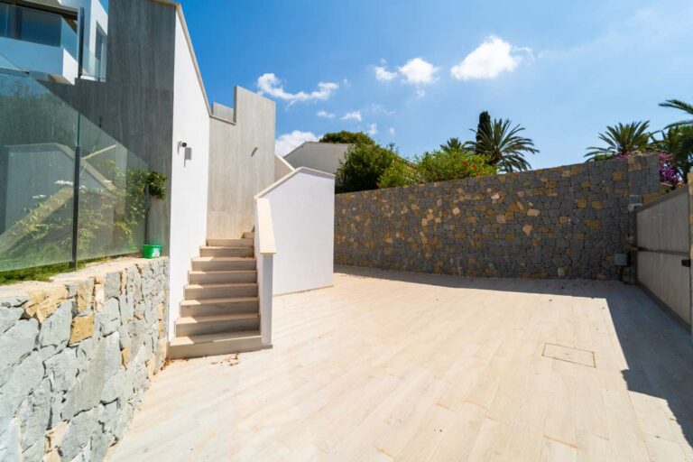 Außentreppe an einer neu gebauten Luxusvilla in der Nähe des Yachthafens Puerto Blanco in Calpe mit Steinmauer, moderner Fassade und geräumiger Terrassenfläche