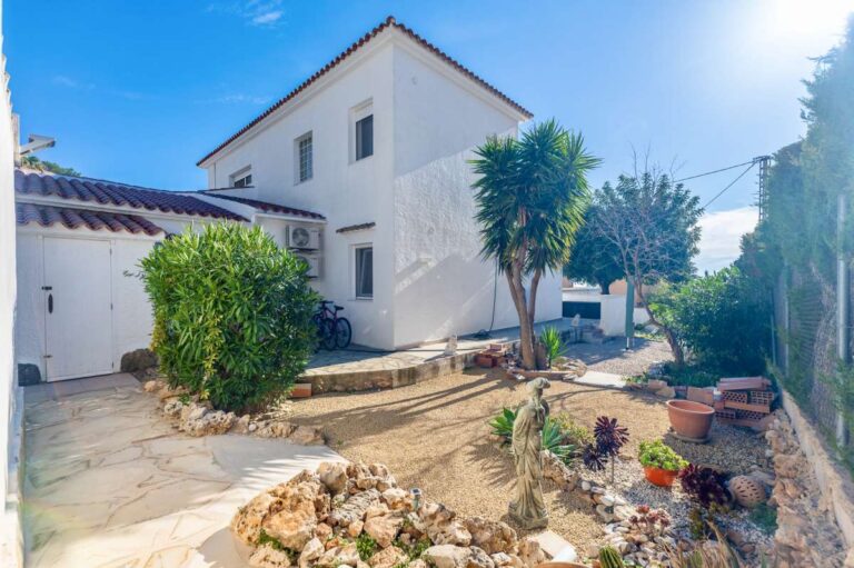 Exterior view of a contemporary villa in Calpe with garden area, white facade and surrounding terrace.