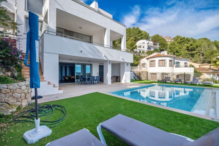 Exterior view of a modern spacious villa in Calpe with private swimming pool, lawn area and terrace.