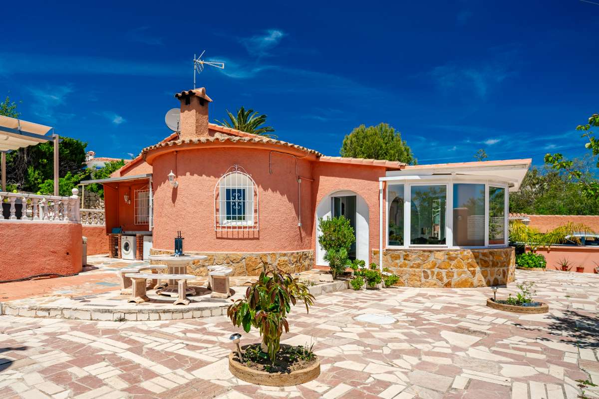 Exterior view of a renovated Mediterranean villa in La Cometa, Calpe with paved terrace and glazed dining area.