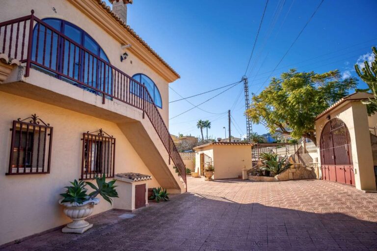 Exterior view of a spacious villa with guest apartments, arched windows and parking area in Calpe.
