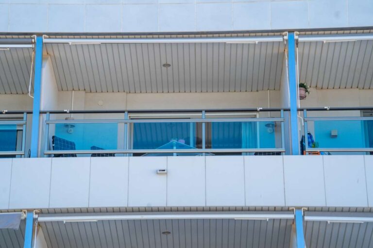 Exterior view of the terrace at a beachfront apartment by La Fossa Beach in Calpe with blue railings and covered balcony area