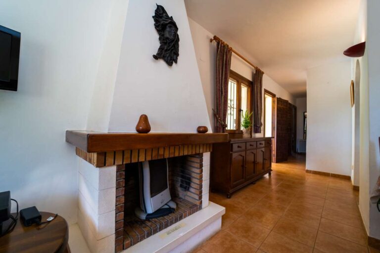 Fireplace and interior hallway with traditional wooden furniture inside a Mediterranean villa in Cometa III, Calpe.