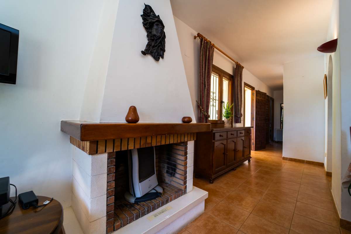 Fireplace and interior hallway with traditional wooden furniture inside a Mediterranean villa in Cometa III, Calpe.