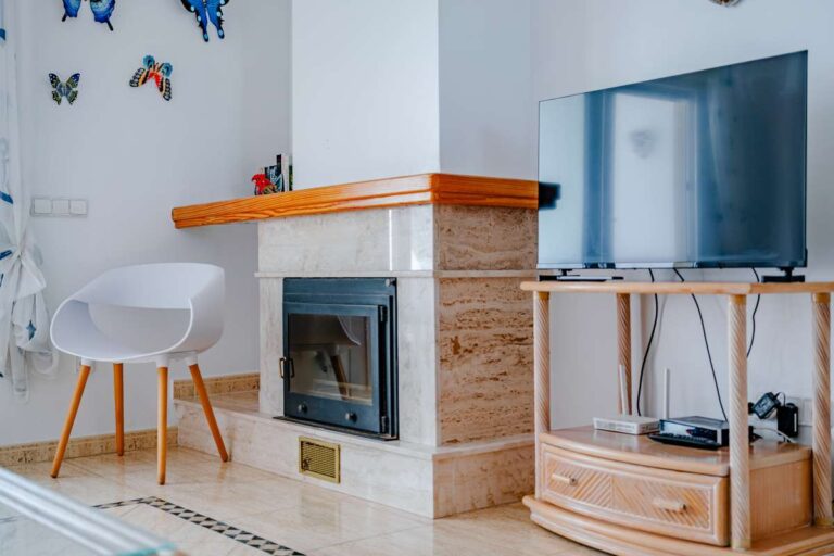 Fireplace and TV area inside a duplex apartment near Les Platgetes Beach in Moraira with modern seating, bright white interior and coastal decor