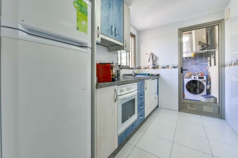 Fitted kitchen inside a beachfront La Fossa apartment in Calpe with appliances, tiled floor and utility area