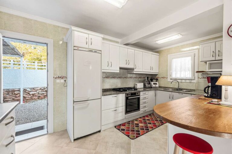 Fitted kitchen with breakfast bar and terrace access inside a contemporary villa in Calpe.