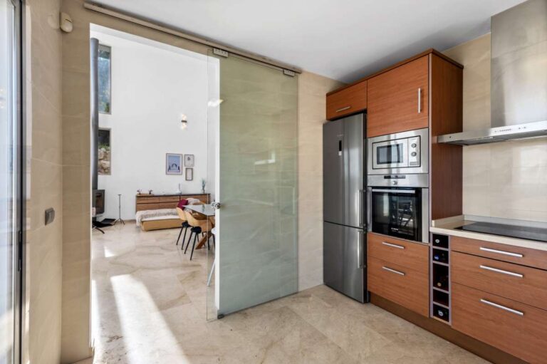 Fitted kitchen with terrace access and modern appliances inside a spacious villa with panoramic sea views in Calpe.