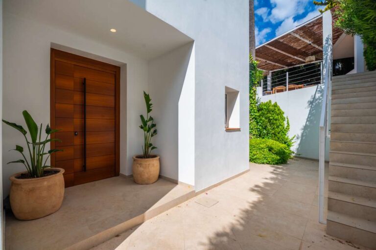 Front entrance at a modern villa in Altea Hills with wooden door, potted plants, exterior stairs and white contemporary façade