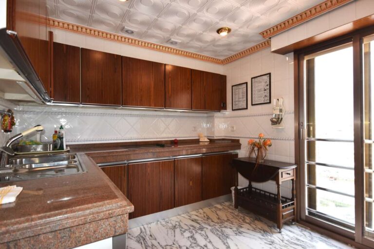 Fully equipped kitchen with wooden cabinetry and quality finishes inside a frontline double penthouse on Arenal Beach in Calpe.