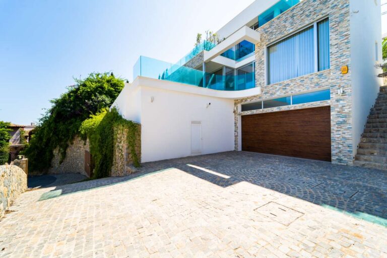 Garage and driveway at a luxury villa in Calpe with stone façade, private parking area and modern exterior design