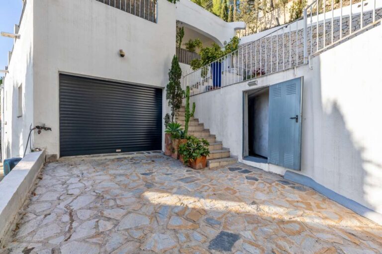 Garage and driveway at a panoramic sea view villa in Benissa with stone paving, exterior stairs and private parking area