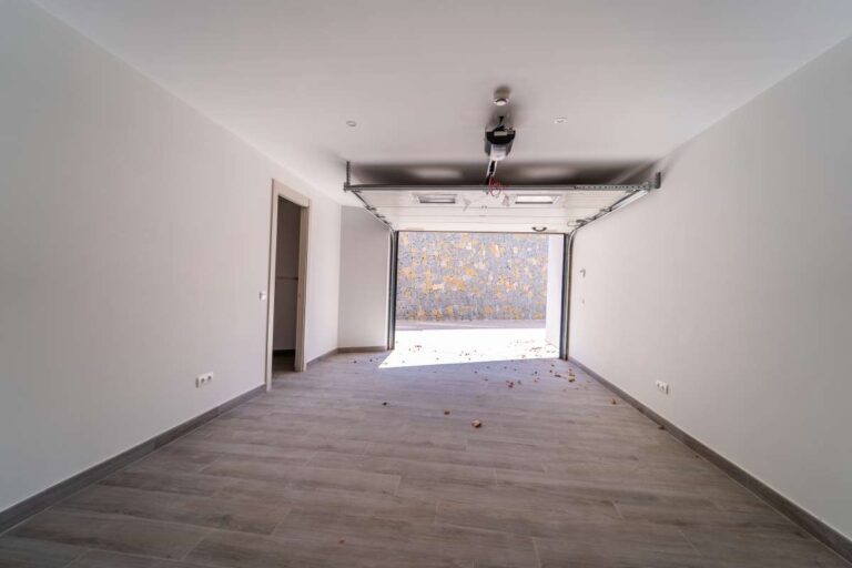 Garageninterieur einer neu gebauten Luxusvilla in der Nähe des Yachthafens Puerto Blanco in Calpe mit automatischem Tor, offenem Parkplatz und moderner Ausstattung