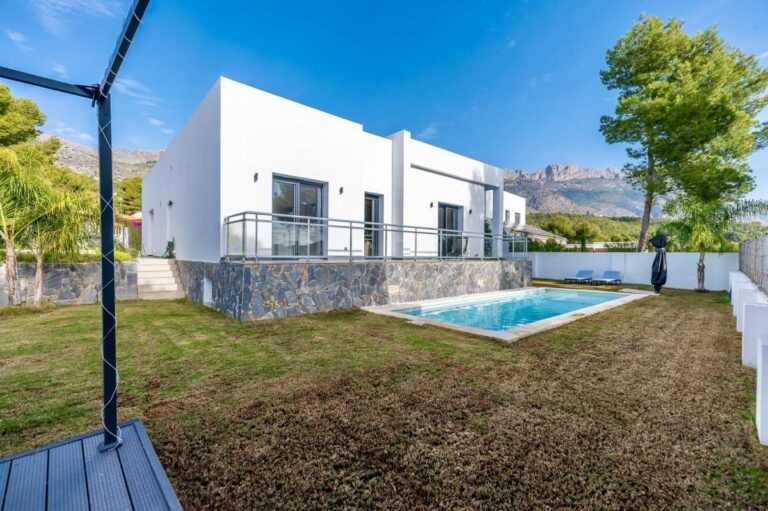 Garden and pool area at a single-level modern villa in Santa Clara, Altea with saltwater swimming pool, white exterior, lawn and mountain views