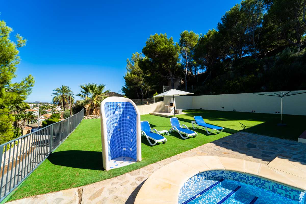 Garden and pool area with sun loungers and mountain surroundings at a Mediterranean villa in Cometa III, Calpe.