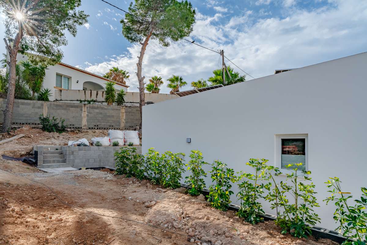 Garden area beside a new build villa for sale in Calpe with surrounding trees and boundary walls