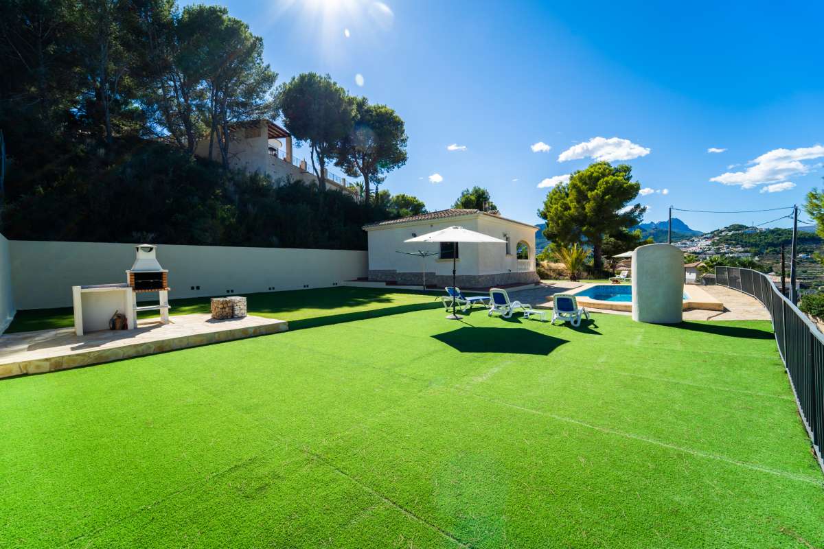 Garden area with barbecue, sun loungers and artificial lawn at a Mediterranean villa in Calpe.