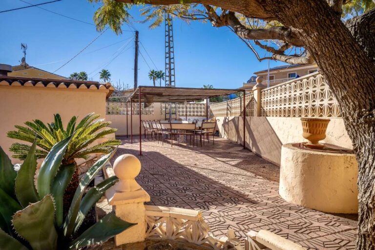 Garden area with boundary wall, mature tree and Mediterranean planting at a spacious villa with guest apartments in Calpe.