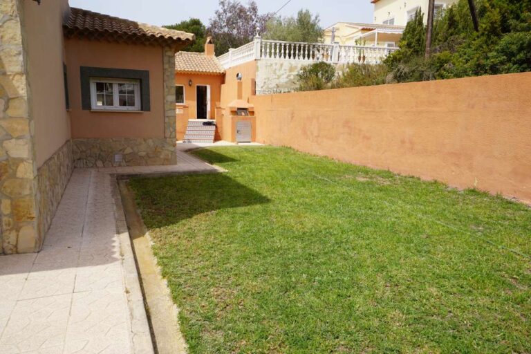 Garden area with lawn and exterior view of a Mediterranean villa in Calpe near La Calalga Beach.
