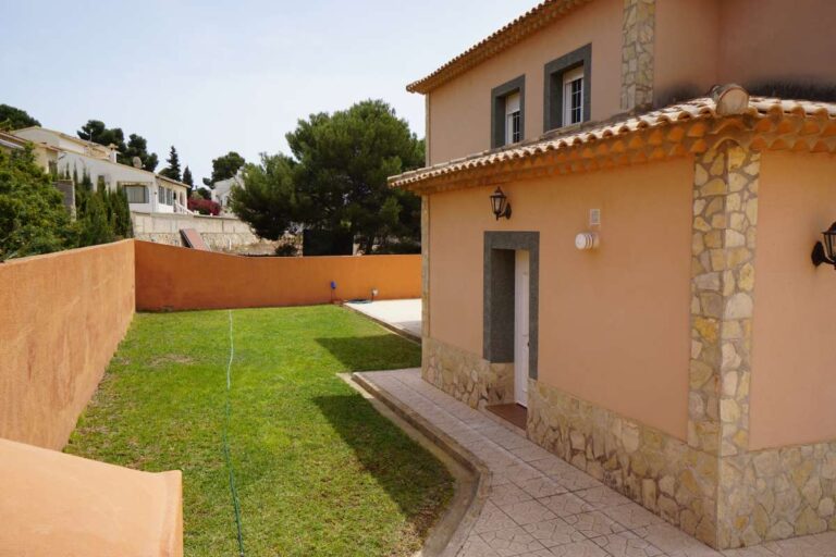Garden area with lawn and exterior view of a Mediterranean villa near La Calalga Beach in Calpe.