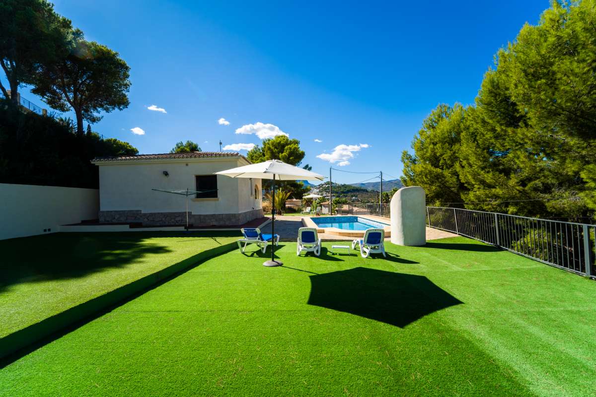 Garden area with mountain views, sun loungers and barbecue area at a Mediterranean villa in Calpe.