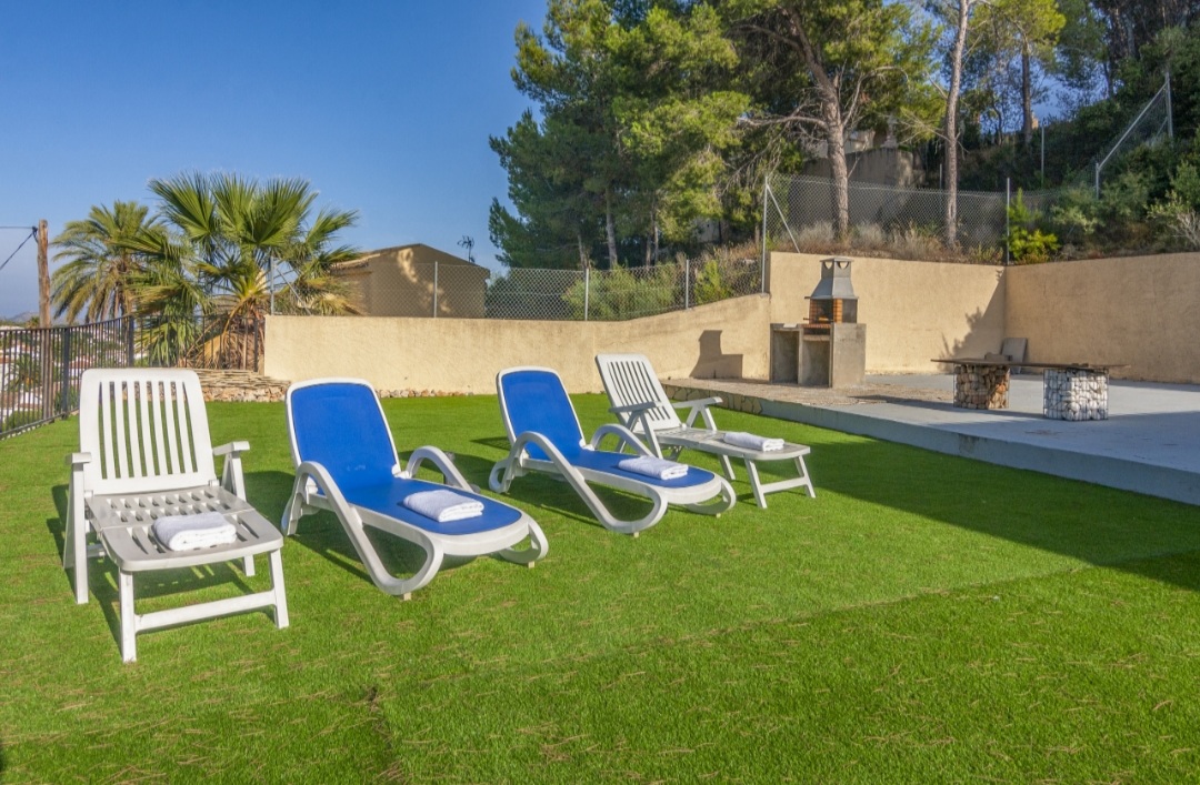 Garden area with sun loungers, private pool and mountain surroundings at a Mediterranean villa in Calpe.