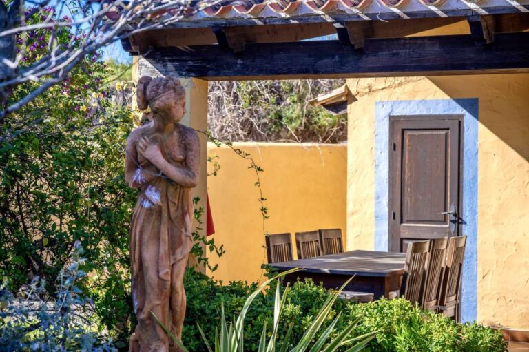 Garden detail at a traditional Spanish finca near Moraira with statue, mature planting, rustic exterior wall and shaded outdoor area