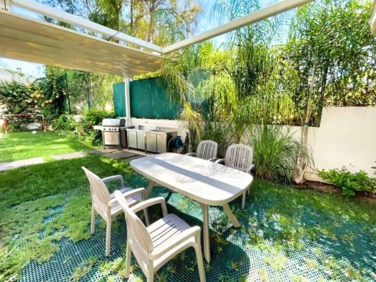 Garden dining area at a modern luxury villa in La Calalga, Calpe with outdoor table, summer kitchen, pergola and landscaped greenery